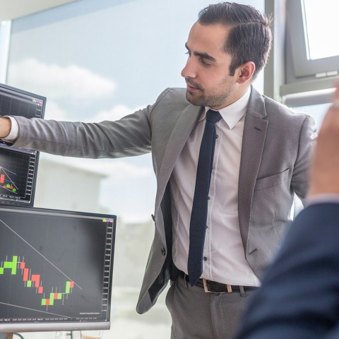 Hombre presentando gráficas financieras en una pantalla, representando el enfoque analítico y profesional del certificado en Mercado de Valores de la USFQ.
