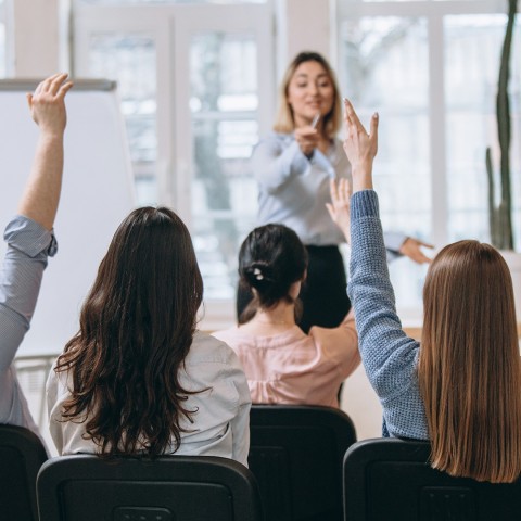 Oradora dando una presentación en un salón, representando las habilidades de comunicación y persuasión enseñadas en el curso de Técnicas de Venta de la USFQ.