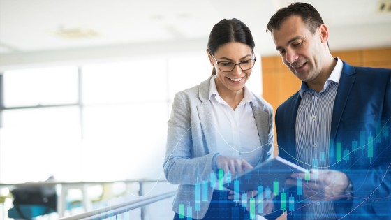 Profesionales viendo gráficos financieros en una tablet, que simbolizan el enfoque estratégico y analítico del curso de Inteligencia Financiera de la USFQ.