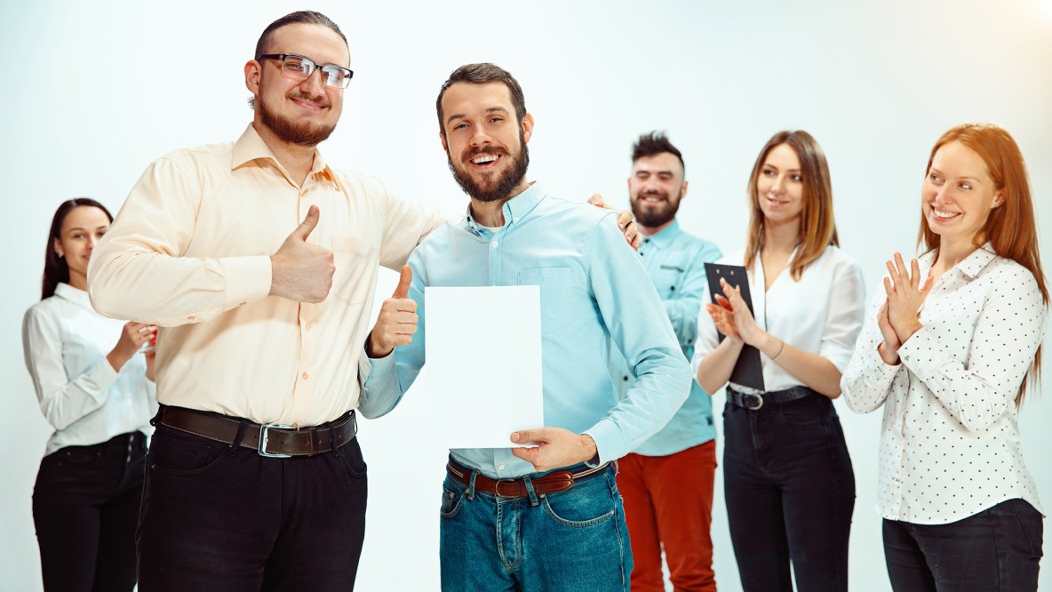 Jefe aprobando y felicitando a un joven empleado exitoso durante una reunión de trabajo, representando reconocimiento profesional y buen clima laboral