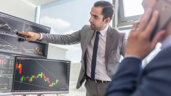Hombre presentando gráficas financieras en una pantalla, representando el enfoque analítico y profesional del certificado en Mercado de Valores de la USFQ.