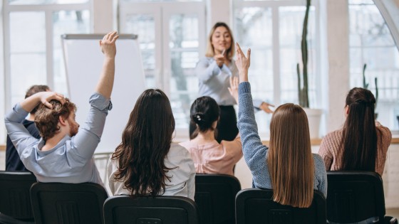 Oradora dando una presentación en un salón, representando las habilidades de comunicación y persuasión enseñadas en el curso de Técnicas de Venta de la USFQ.